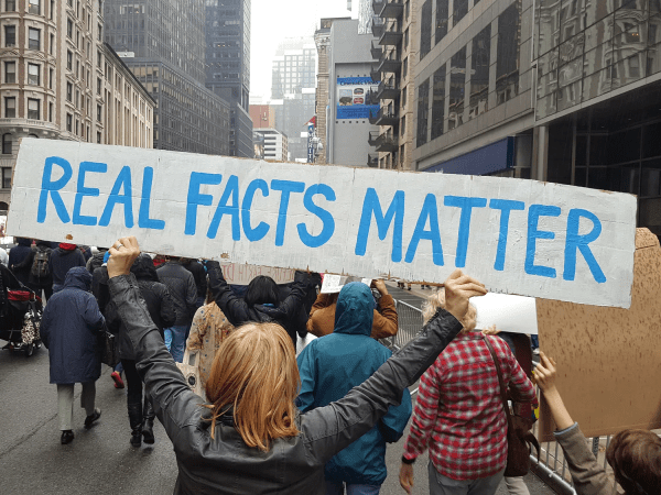A protester holding a sign reading "Real Facts Matter"