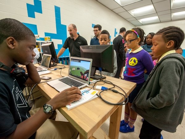 Children gathered around computers at a Baltimore school during the local launch of Comcast's Internet Essentials program