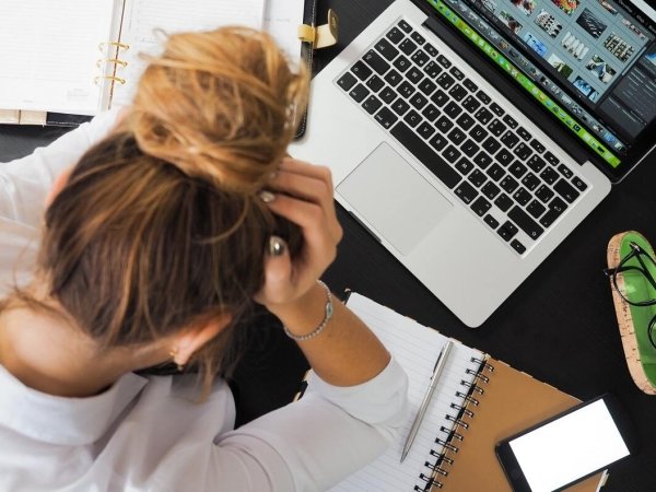 Woman sitting in front of laptop with head in hands