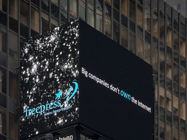 Electronic Times Square billboard with the Free Press logo on one side and "Big companies don't own the internet" on the other