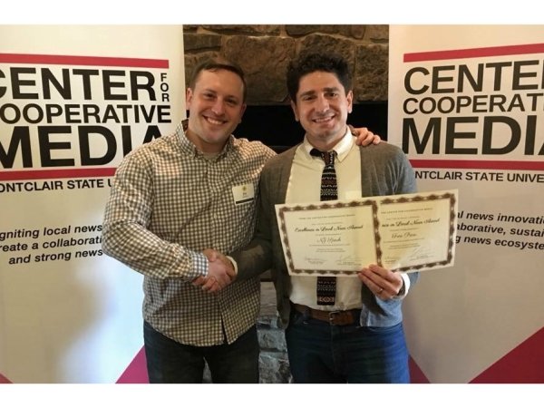 News Voices: New Jersey Director Mike Rispoli holds an award while shaking a man's hand.