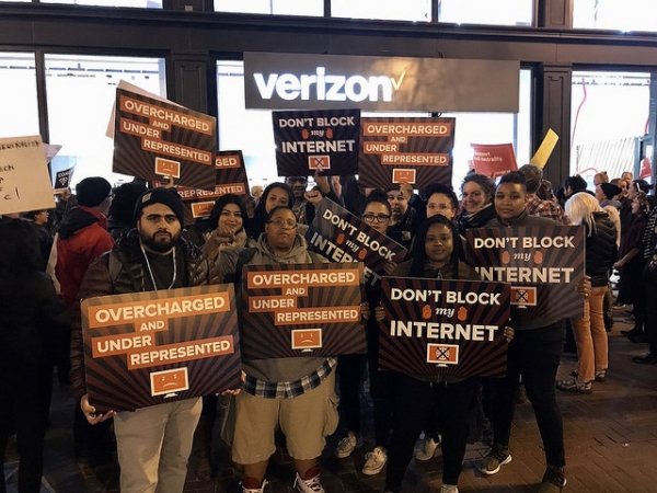 San Francisco protesters holding "Overcharged and underrepresented" and "Don't block my internet" signs