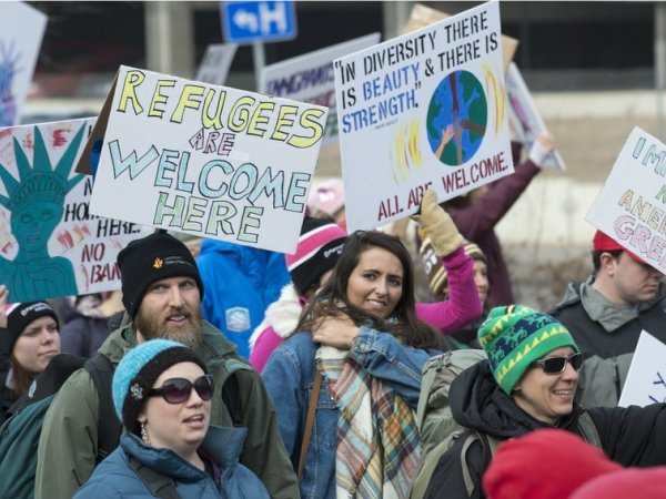 Activists holding signs reading "Refugees welcome"