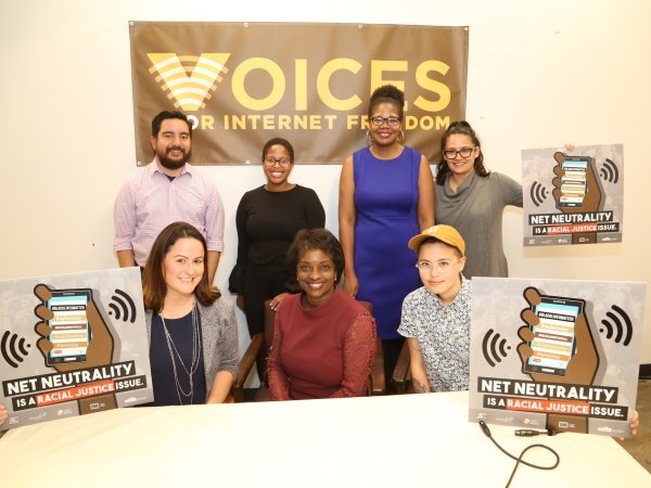 Seven people seated before a "Voices for Internet Freedom" sign