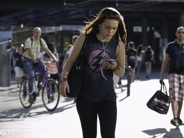 Woman walking down street while looking at cellphone