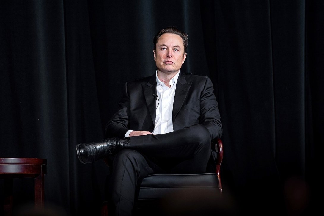 Twitter CEO Elon Musk sitting in a chair against a black background