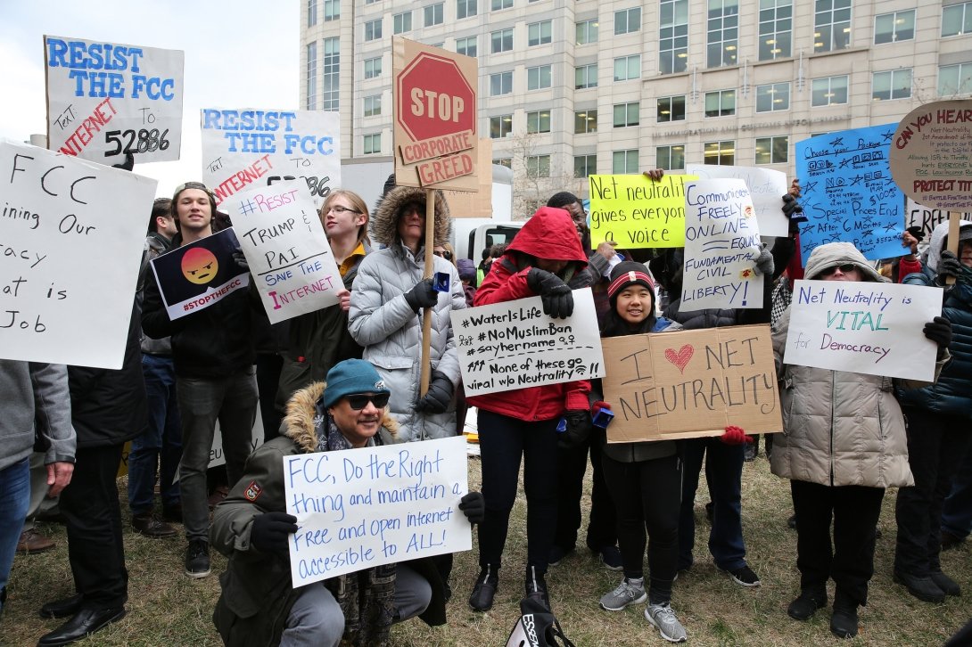 Net Neutrality activists holding signs with messages like "FCC, do the right thing and maintain a free and open internet accessible to all"