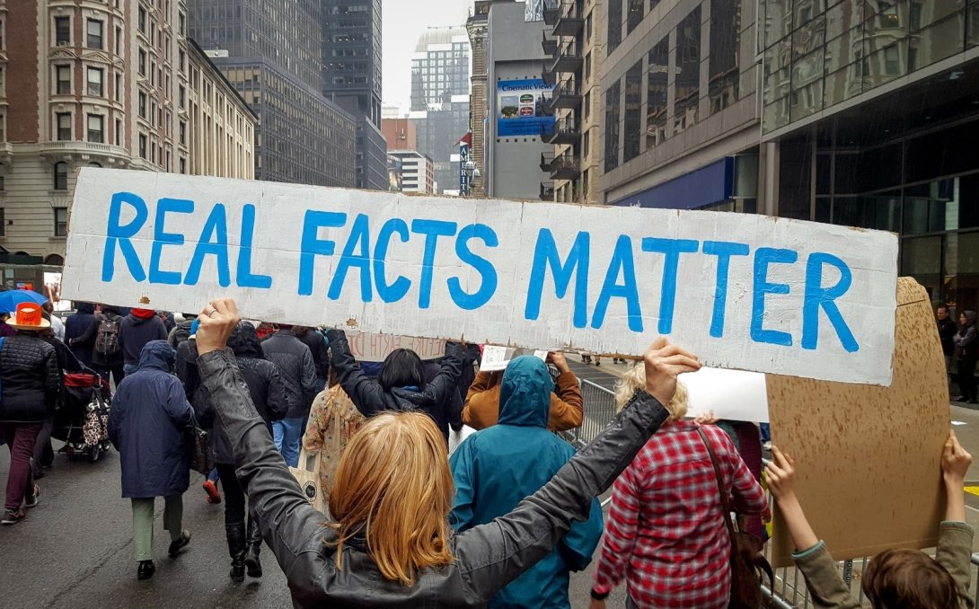 Protesters holding a banner reading "Real Facts Matter"