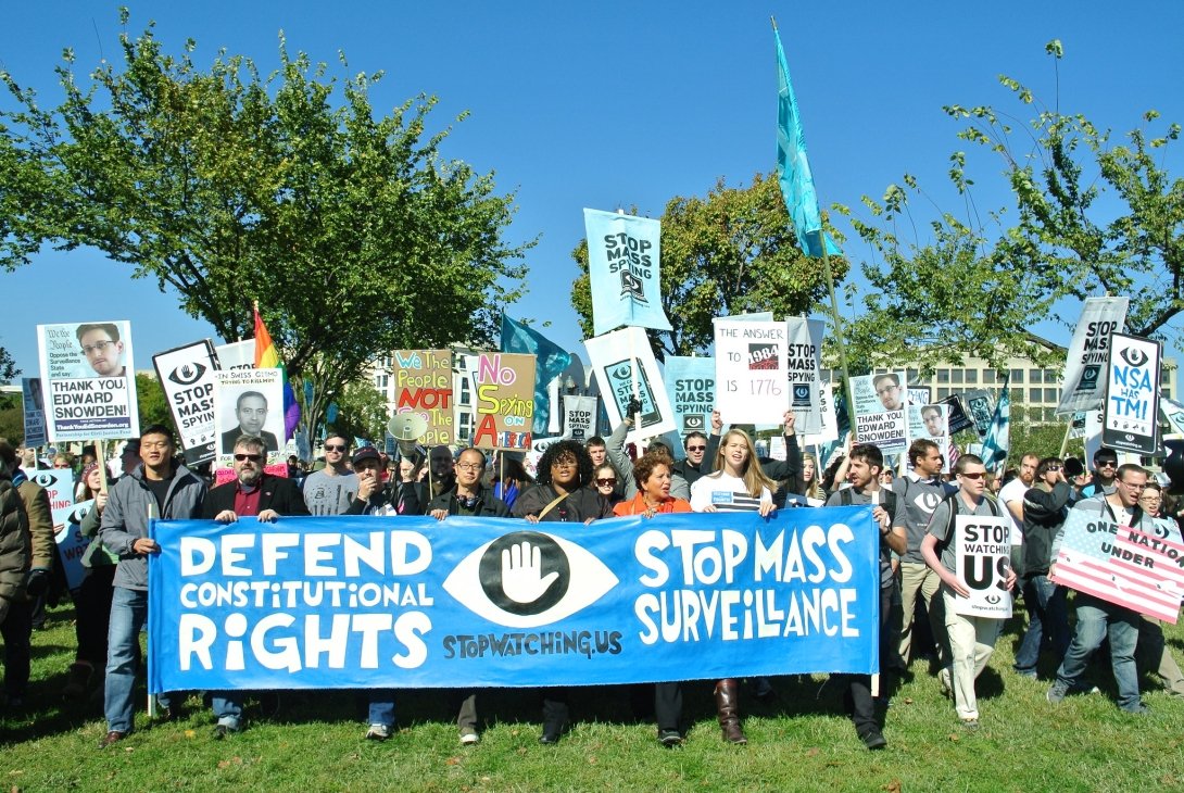 Protesters holding banner reading "Defend Our Rights. Stop Mass Surveillance."
