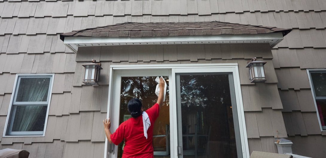 Maricela Bendito washing the windows of a house in New Jersey.