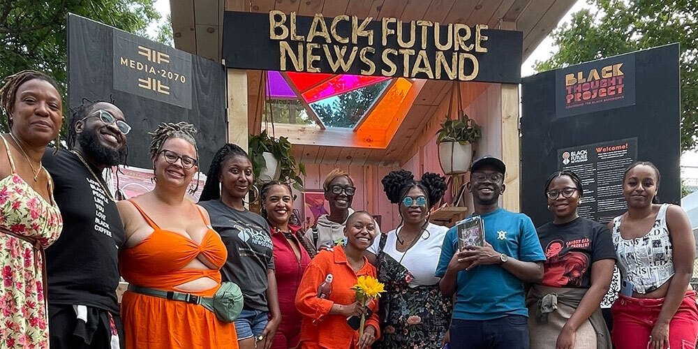 Organizers and supporters standing in front of the Black Future Newsstand installation