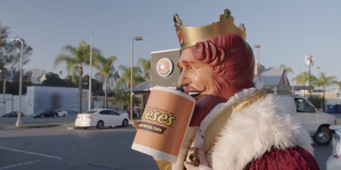 Burger King character drinking from oversized Reese's mug