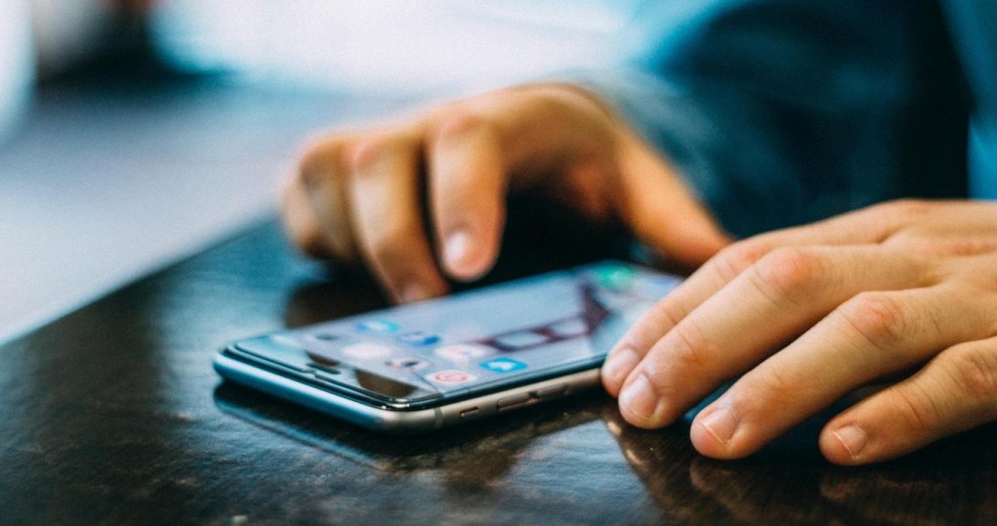 Hands resting on table on either side of cellphone