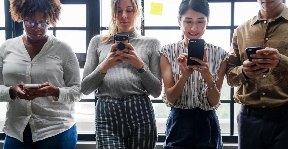 Three women and one man using their phones
