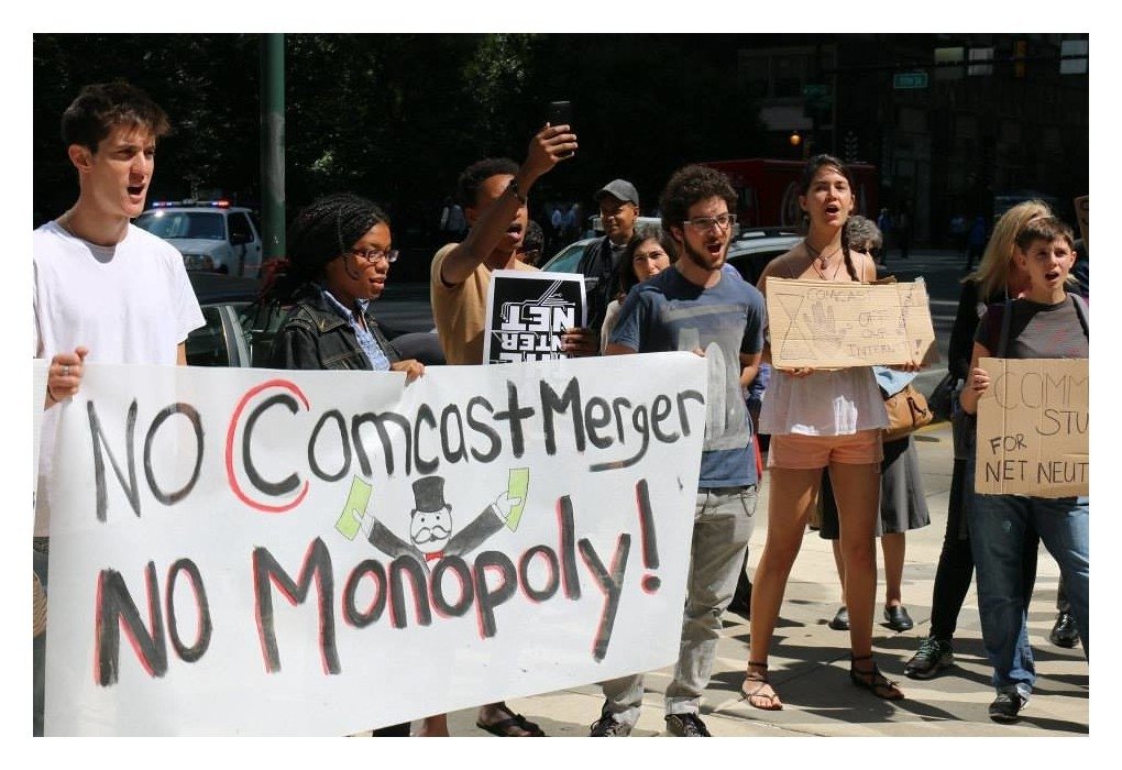Philly activists holding poster reading "No Comcast merger / no monopoly!"
