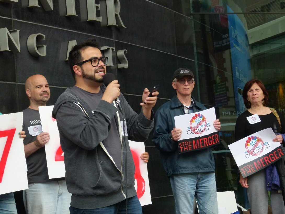 Man speaking into microphone while surrounded by other activists