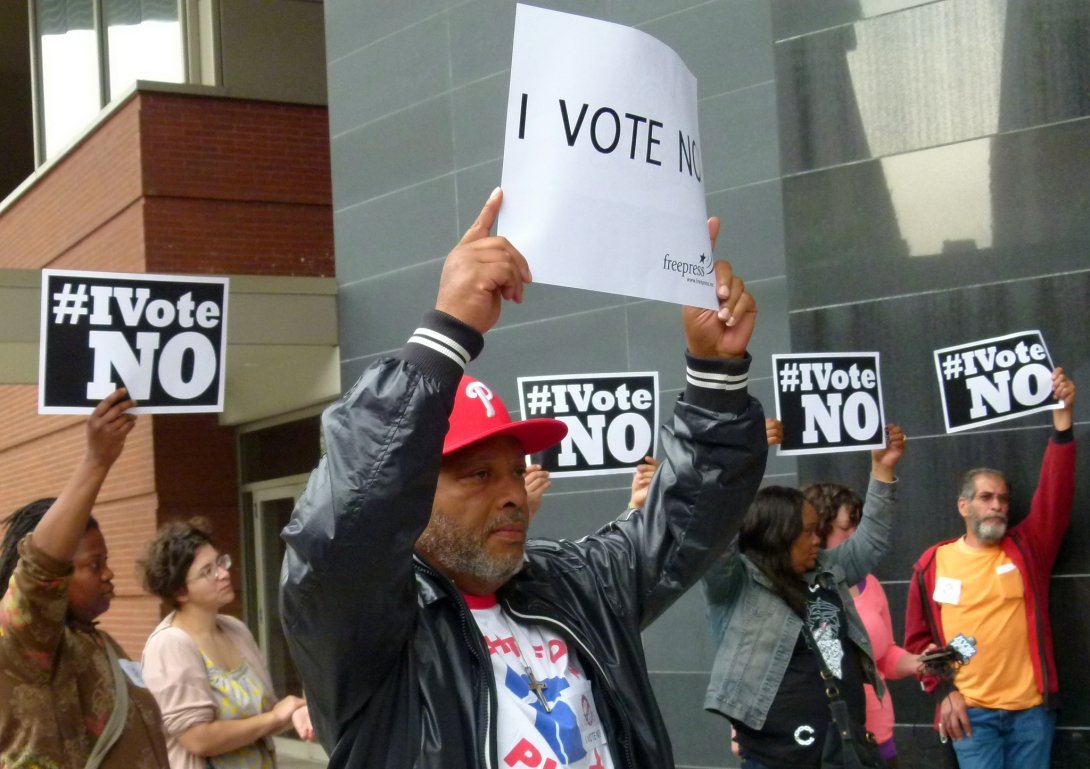 Man holding "I vote no!" sign surrounded by other activists