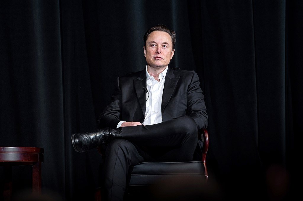 Elon Musk sitting in a chair on a stage at the U.S. Air Force Academy in Colorado