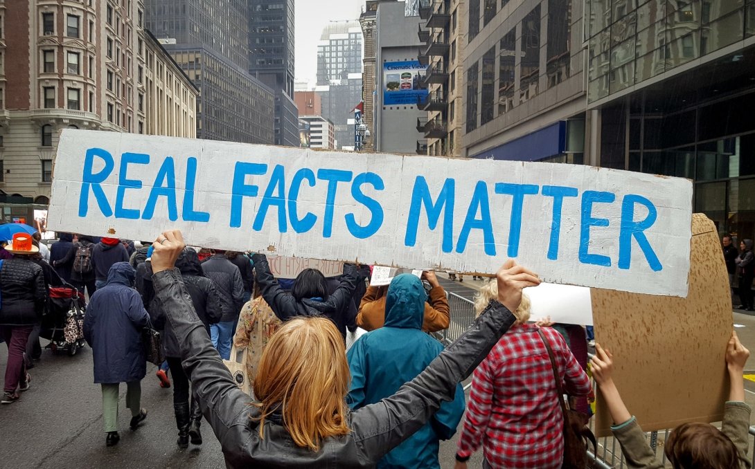 Protester holding a sign reading "Real Facts Matter"