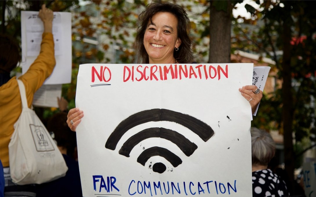 Activist holding "No discrimination/fair communication" poster
