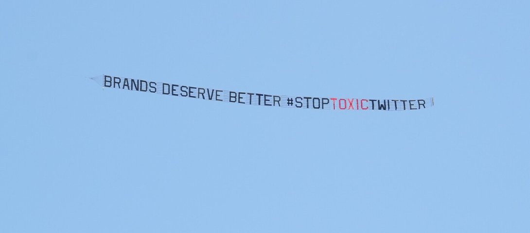 A banner flying over a Miami convention where Musk appeared reads "Brands deserve better. #StopToxicTwitter"
