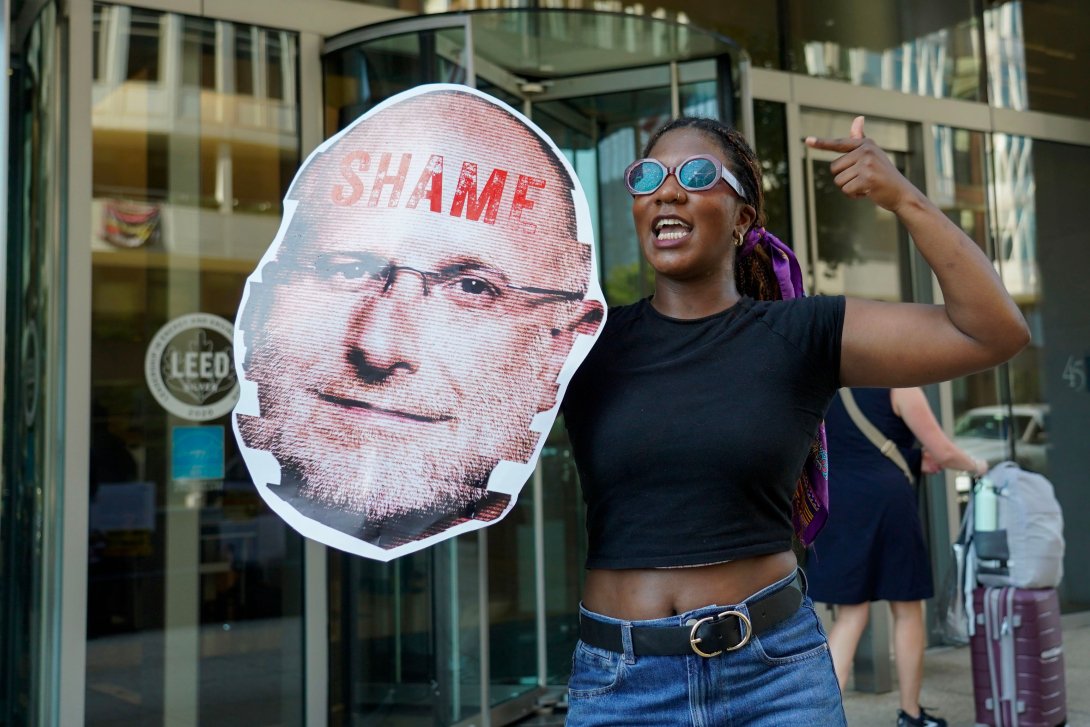 Activist holding a sign with a photo of FCC Chairman Carr and the word "Shame"