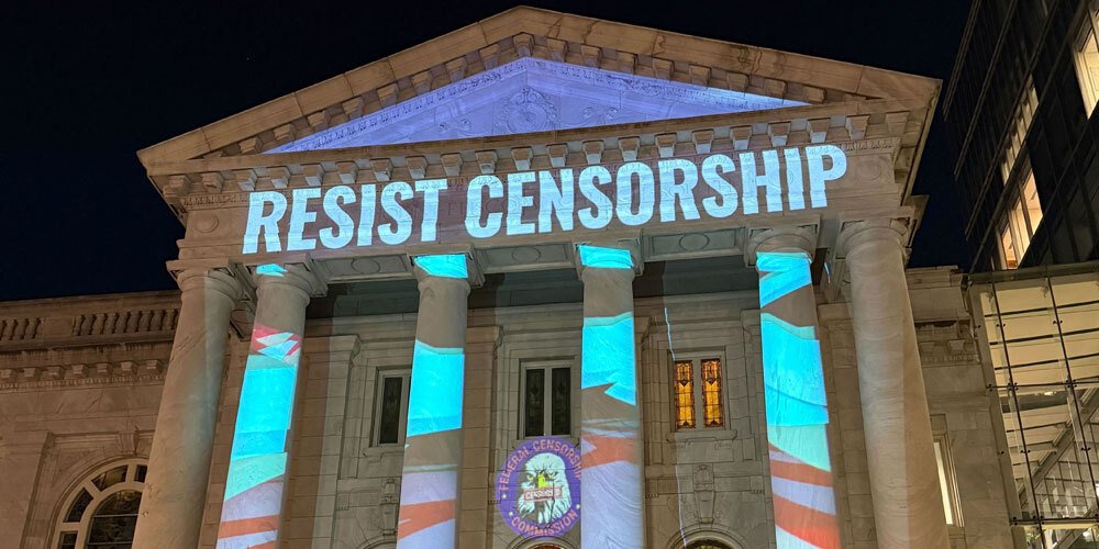 The text "Resist Censorship" projected on the pillars of a building