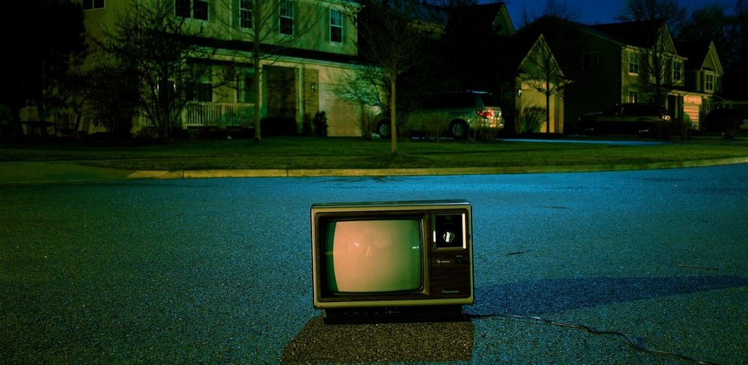 A television set on the road in the middle of a neighborhood at night