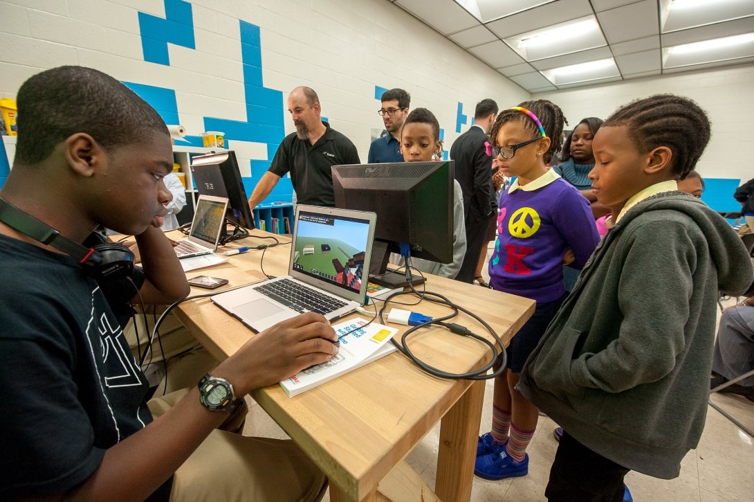 Children gathered around computers at a Baltimore school during the local launch of Comcast's Internet Essentials program