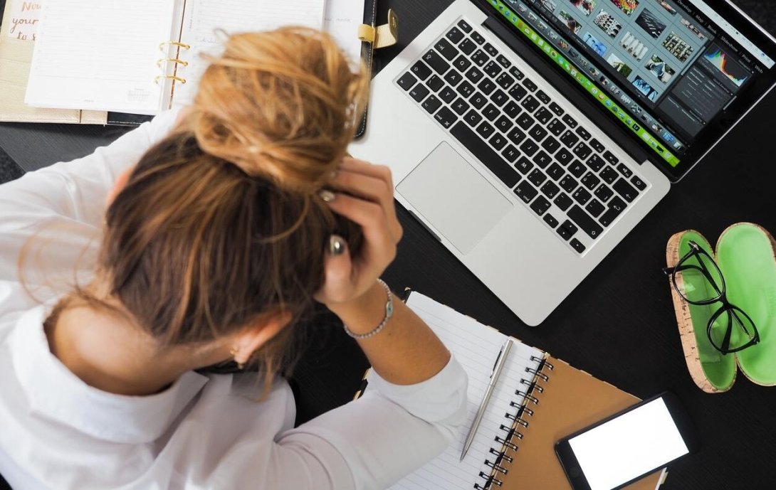 Woman sitting in front of laptop with head in hands
