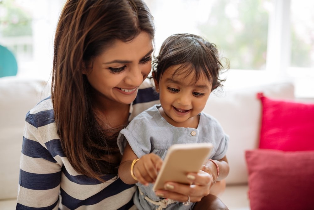 Mother and child look down at cell phone