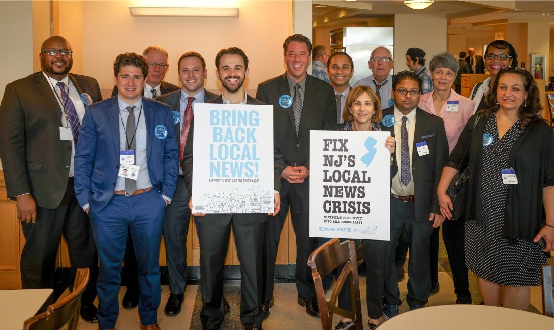 Group of people holding signs reading "Bring back local news" and "Fix NJ's local news crisis"