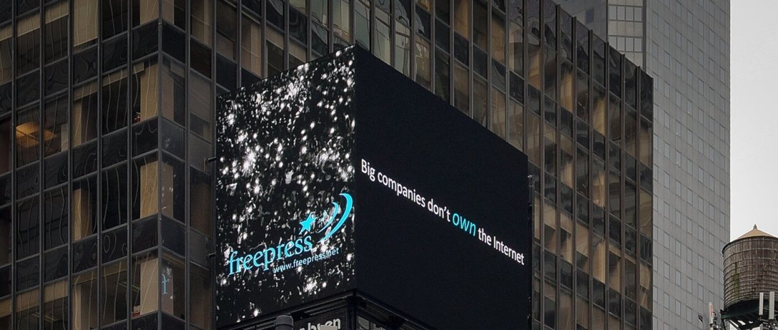 Electronic Times Square billboard with the Free Press logo on one side and "Big companies don't own the internet" on the other