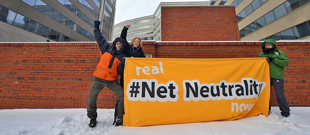 Net Neutrality activists holding sign reading "Real Net Neutrality now"