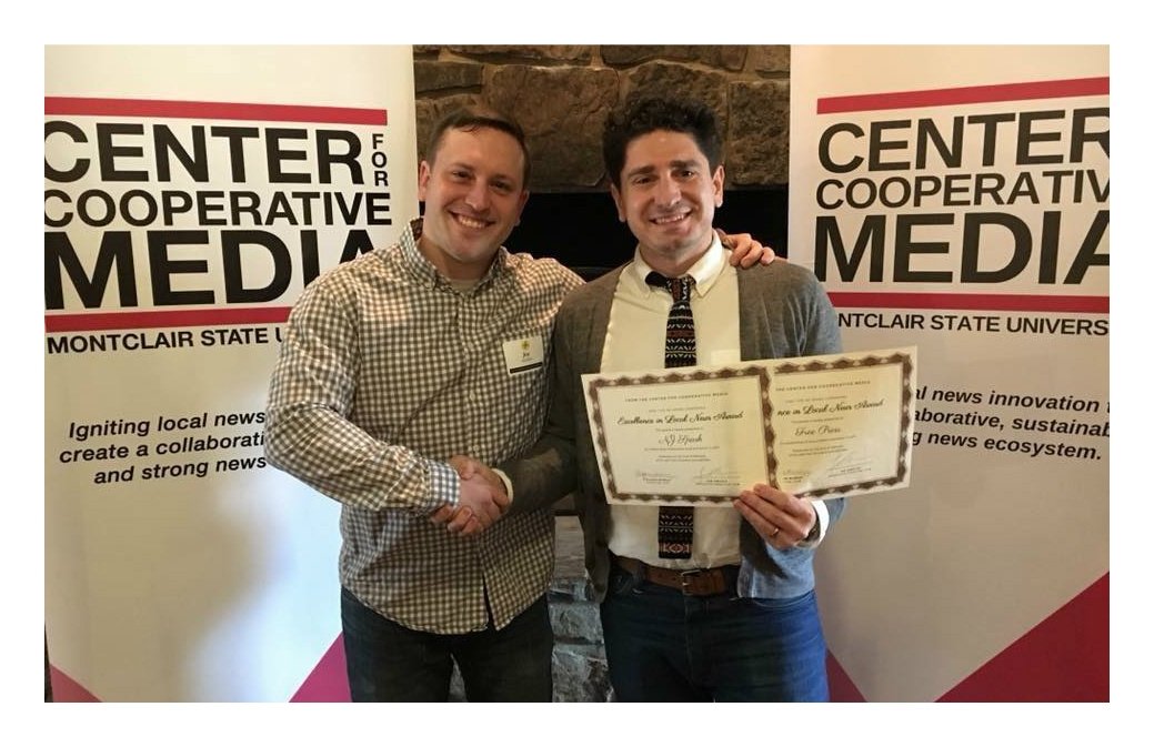 News Voices: New Jersey Director Mike Rispoli holds an award while shaking a man's hand.