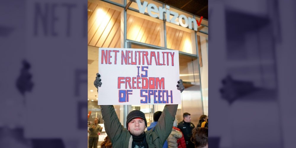 Net Neutrality activist in NYC holding a poster reading "Net Neutrality is freedom of speech"