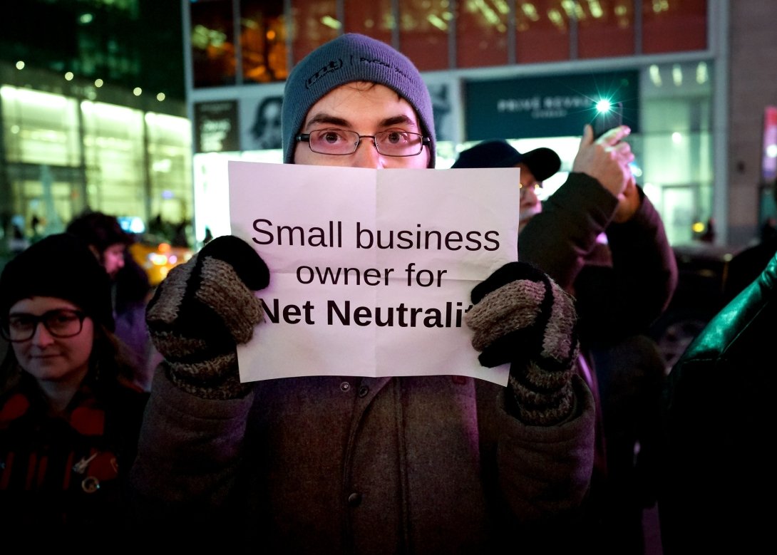 Activist holding sign reading "Small business owner for Net Neutrality"