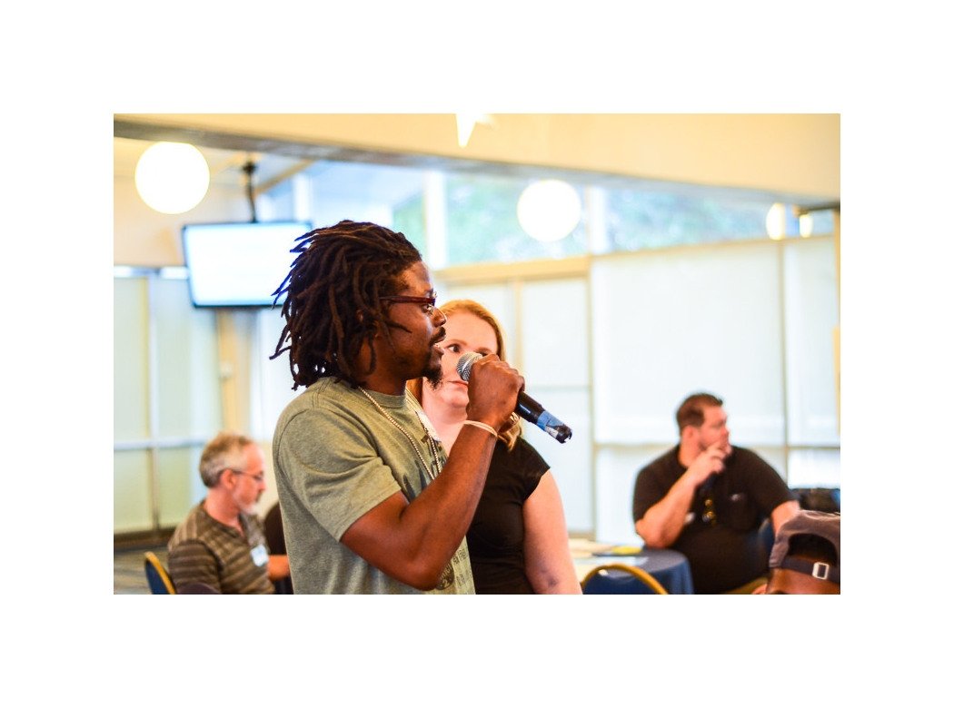 Man speaking into microphone next to woman