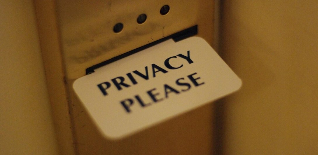 "Privacy please" sign extending from slot in hotel-room door