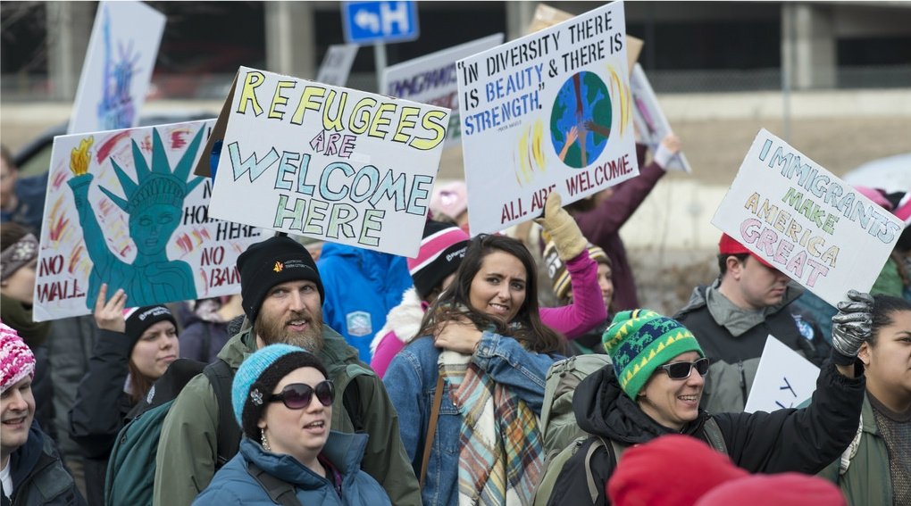 Activists holding signs reading "Refugees welcome"