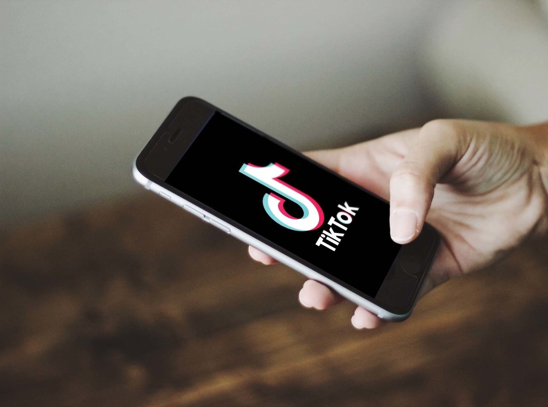 A hand holding an iPhone displaying the TikTok app. A fast-moving bill would result in a ban on TikTok in the United States.