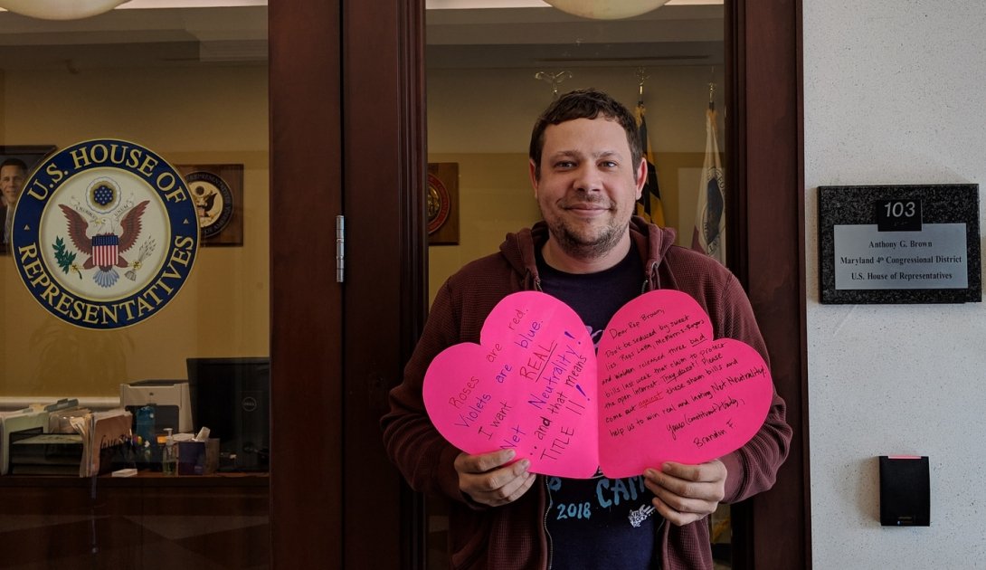 Net Neutrality activist holds a valentine outside Rep. Brown's office.