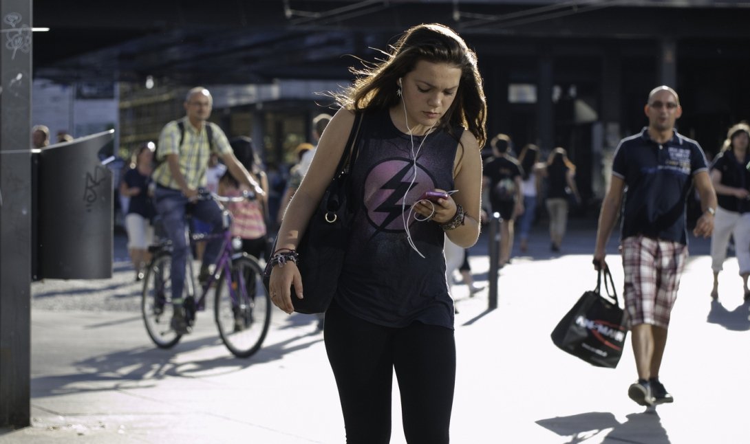 Woman walking down street while looking at cellphone
