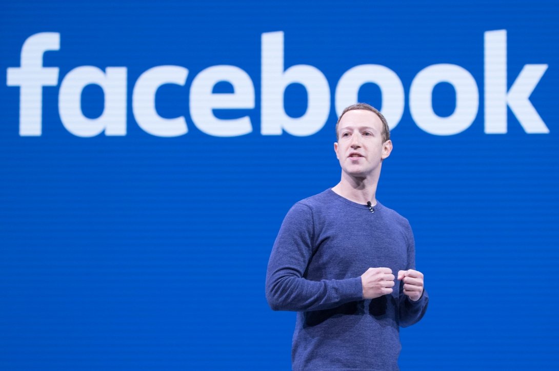 Mark Zuckerberg against a blue screen reading "Facebook"